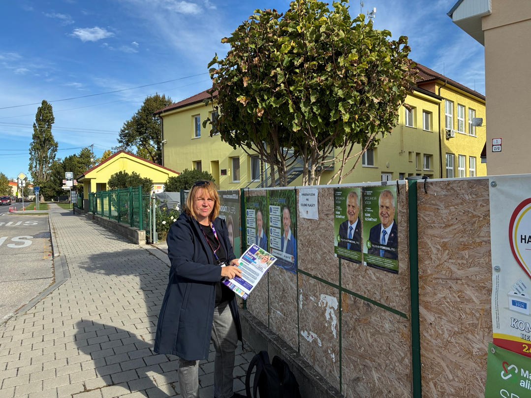 Foto: Veronika Basta pri volebnej plag&aacute;tovej ploche v obci Tom&aacute;&scaron;ov dňa 11.10.2026 počas kampane v obvode č. 24. Autor fotografie: Veronika Fernandes